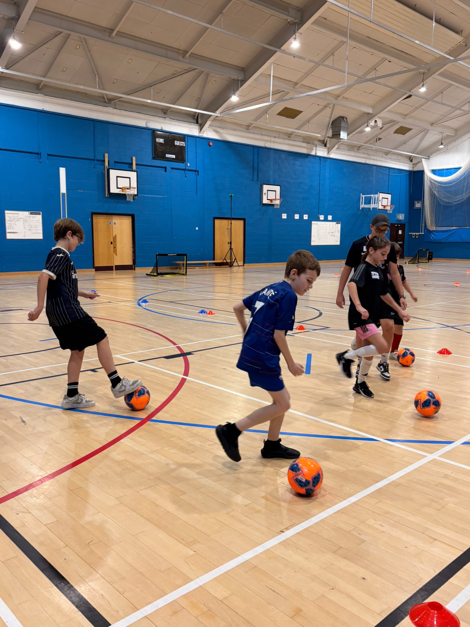 Young players practising football with a coach in an indoor sports hall